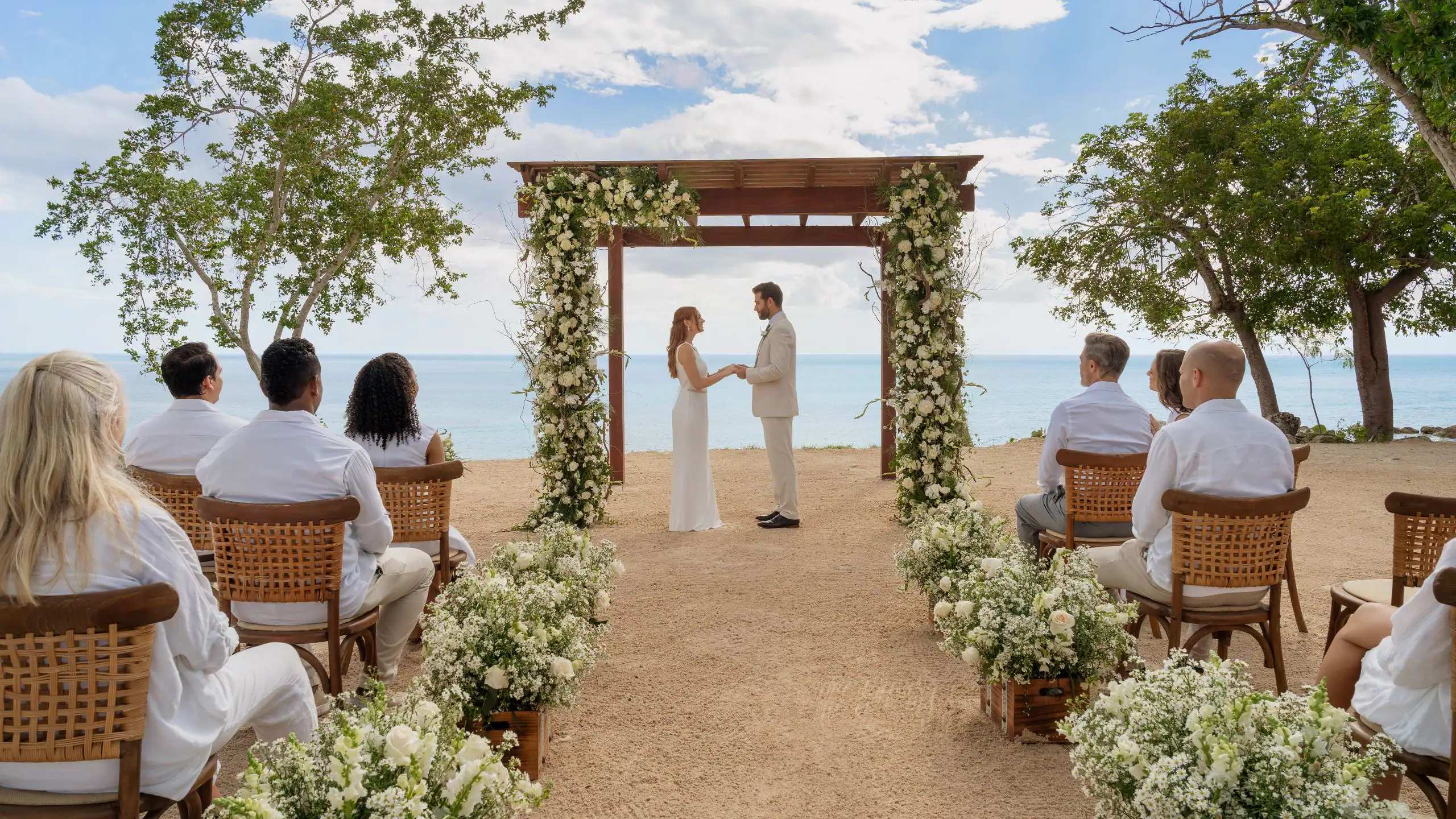 Romantic beachfront wedding ceremony at Dreams La Romana Resort & Spa with ocean views and floral arch décor.