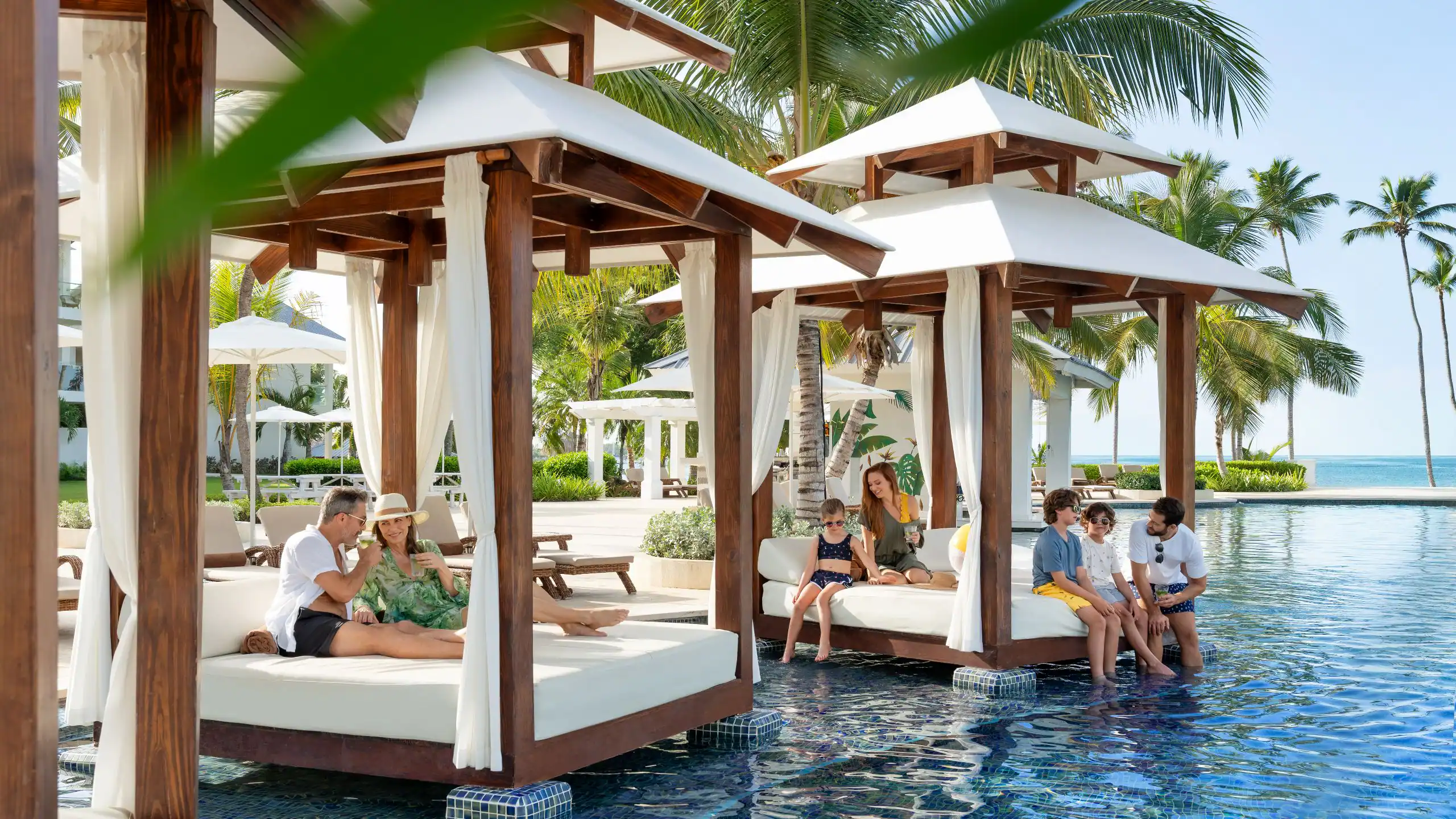 Families relaxing in luxury pool cabanas at Dreams La Romana Resort & Spa with tropical views and oceanfront surroundings.