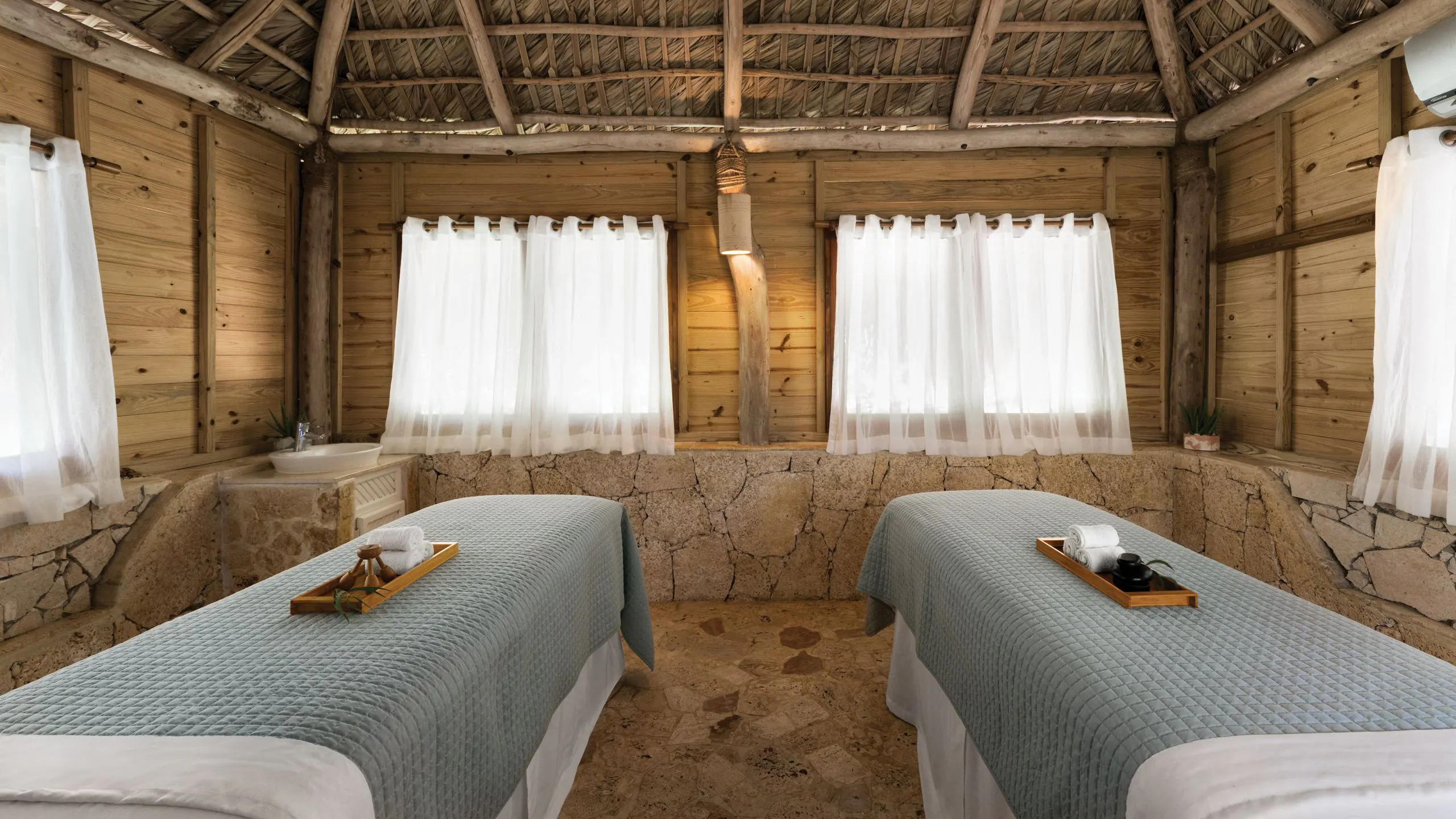 Rustic spa cabana with dual massage tables at Dreams La Romana Resort & Spa, offering a tranquil wellness experience in the Dominican Republic.