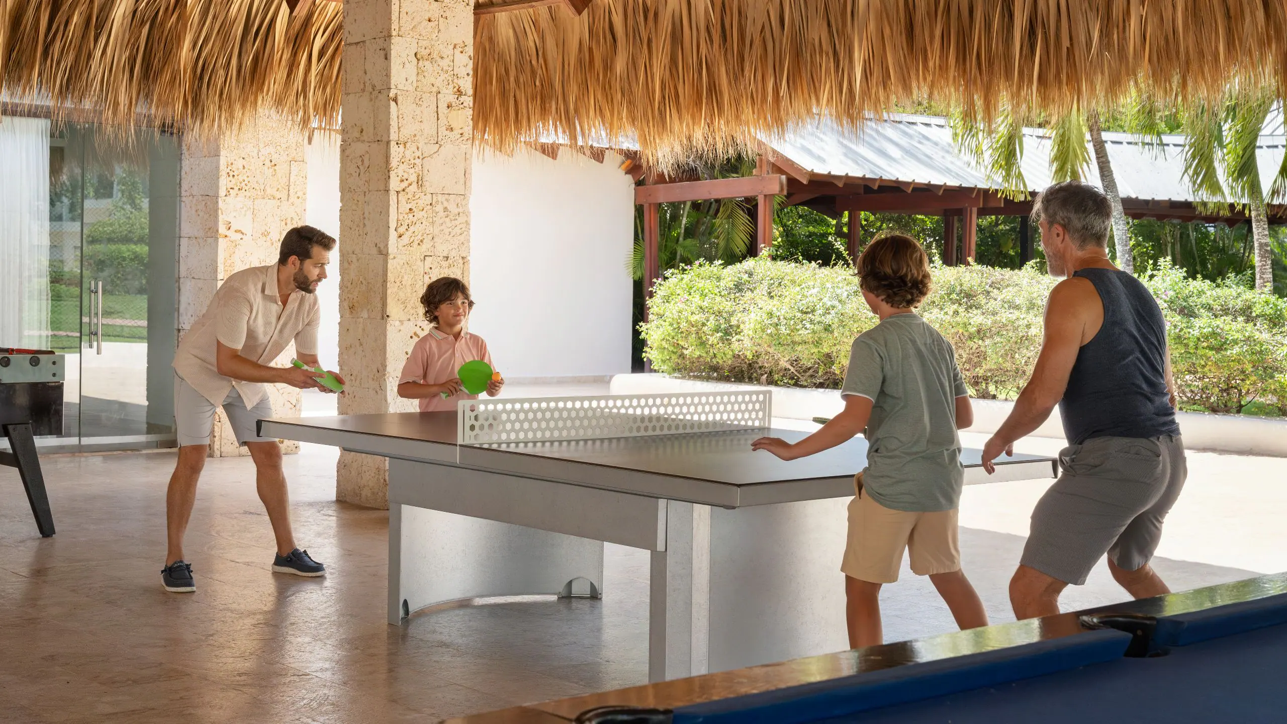 Family enjoying table tennis and games at the teens club area at Dreams La Romana Resort & Spa in the Dominican Republic.